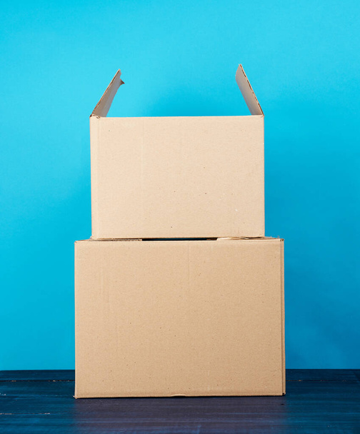 стопка картонных коробок из коричневой крафтовой бумаги на синем деревянном столе, движущаяся концепция
 - Фото, изображение