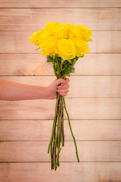 Women hand holding a bouquet of peach Stardust roses variety, studio shot. Yellow flowers - Фото, зображення