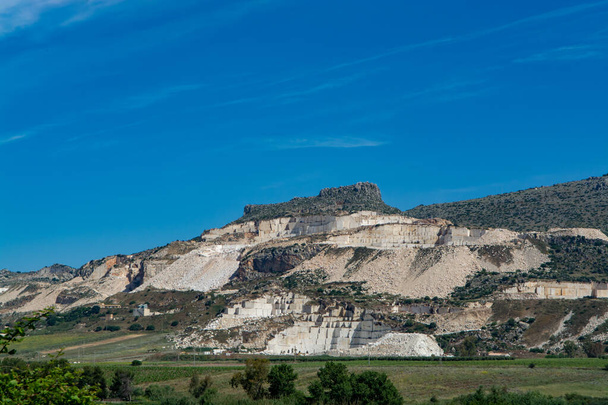 Извлечение Перлато и Перлатино Сицилийского мрамора, ландшафт с мраморными карьерами и виноградниками вблизи Трапани, Сицилия, Италия
 - Фото, изображение
