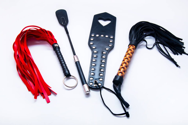 Whip on white background. Accessories for adult sexual games. Toys for BDSM, spanking devices. Spanking and punishment concept. Slave Spank Paddle, bdsm, adult whips. copy space. Set for bdsm - Foto, immagini