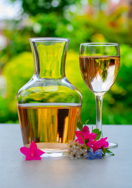 Francia rózsa bor szolgált kertben üvegben és kancsó színes tavaszi virágok a napsütéses napon - Fotó, kép
