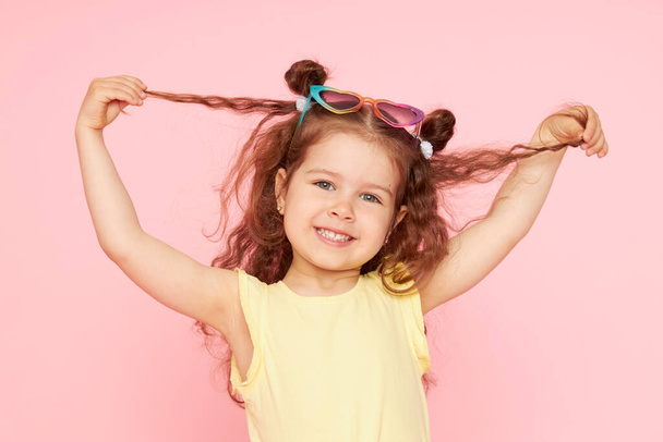 Portrait of a happy child. Cute little girl with a funny face on a pink background. Advertising baby products - Photo, Image
