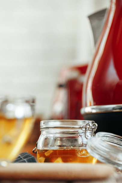 Glass jar of honey on wooden kitchen table - Fotó, kép