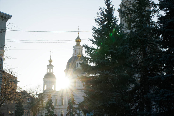 Část ortodoxního kostela před očima se sluncem za okny. Sluneční paprsky pronikají kupolí kostela. Kostelní kříž proti modré obloze - Fotografie, Obrázek