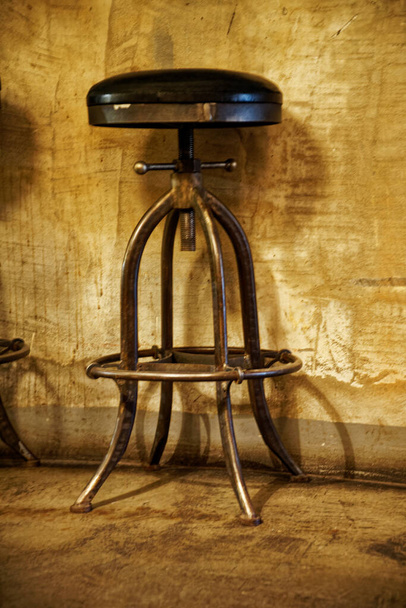Старомодное стальное кресло на деревянном полу у бетонной стены
. - Фото, изображение