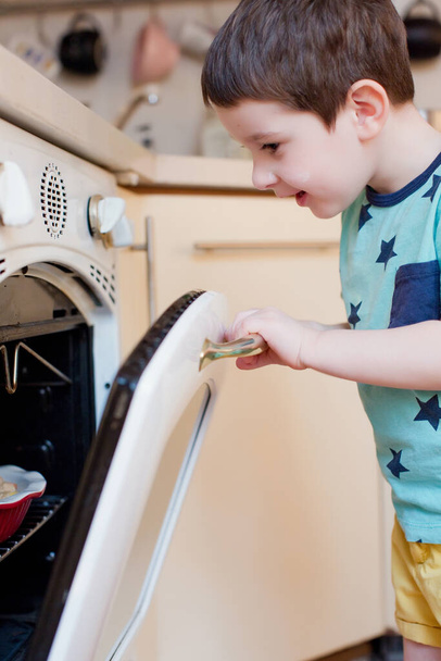 Toddler kid waiting apple pie near oven. Little boy on the kitchen waiting cake - Photo, image