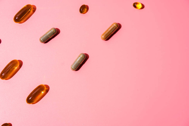 Top view of pills on pink pink background with harsh shadows. Trendy flatlay of preventive medicine - Foto, Bild