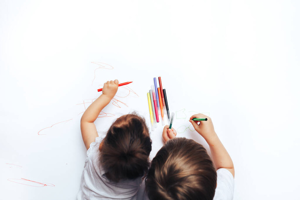 Los niños talentosos dibujan con rotuladores de colores en papel blanco, lecciones, tareas con niños de diferentes edades. plano, vista superior - Foto, imagen