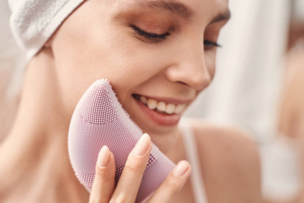Smiling woman performing the skin cleansing procedure - Foto, immagini