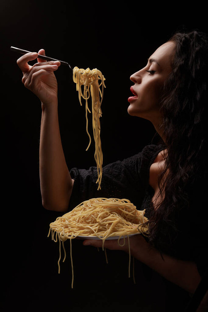 Uma menina bonita come com um espaguete de garfo com lábios vermelhos
. - Foto, Imagem