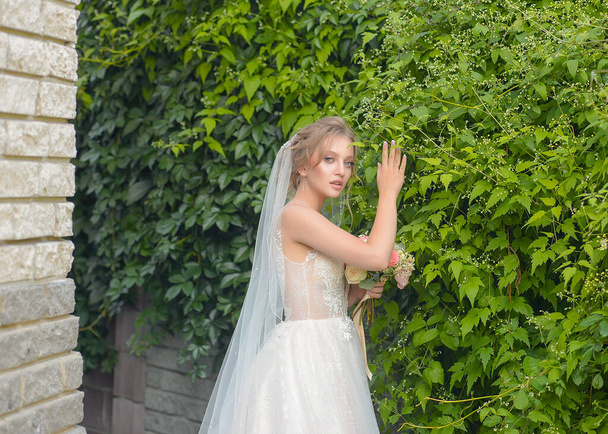 a beautiful Russian bride in a luxurious castle with delicate flowers is getting married and is waiting for her fiance with excitement - Фото, зображення