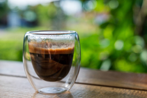 Kopje espresso op tafel. glazen bekerglas voor borrel- of koffiedrankjes. Sluit een glas espresso af. Warme koffie in een glas met dubbele wanden geïsoleerd op een witte achtergrond. - Foto, afbeelding