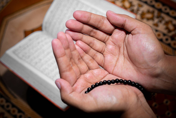 Mujer musulmana joven rezando con Tasbeeh. El Sagrado Corán es el fondo, Interior. Concéntrate en las manos
. - Foto, Imagen