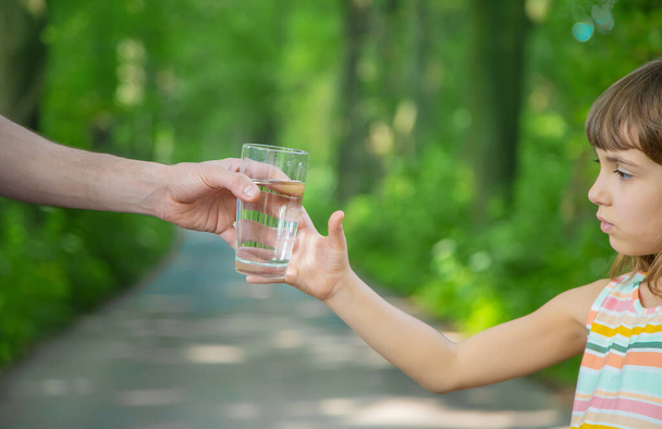 Le père donne à l'enfant un verre d'eau fraîche. Concentration sélective. nature. - Photo, image