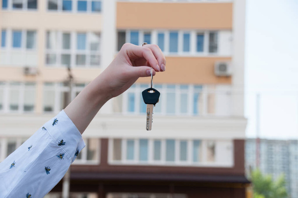 Keys to the apartment in a female hand on background of new homes in the city - Photo, Image