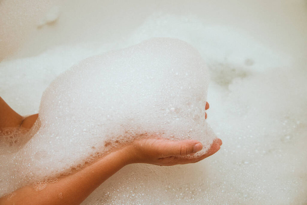 Soap suds on the hands of a child. Baby bath foam. - Photo, Image