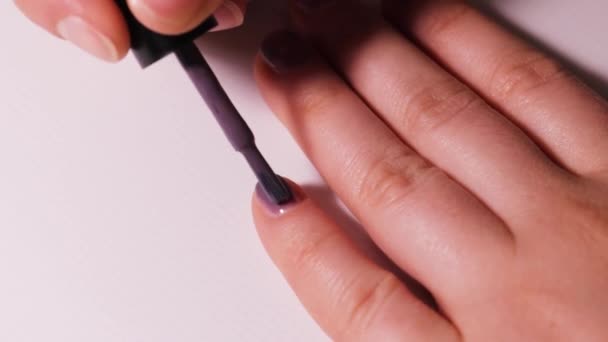 Zastosowanie kolorowego lakieru fioletowego na paznokciu. Manicure w domu. - Materiał filmowy, wideo