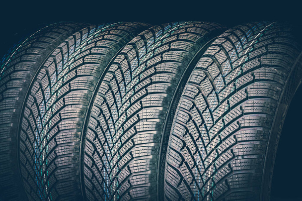 Neumáticos de invierno en fila aislados sobre fondo negro - estilo retro
 - Foto, imagen
