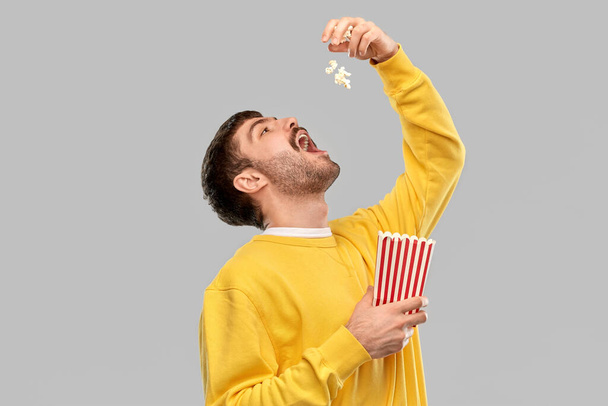 man in yellow sweatshirt eating popcorn - Фото, изображение