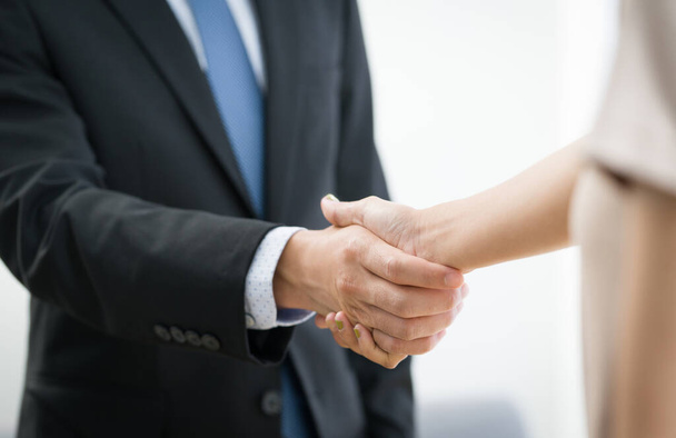 Business partners shaking hands in the modern office. Closeup - 写真・画像