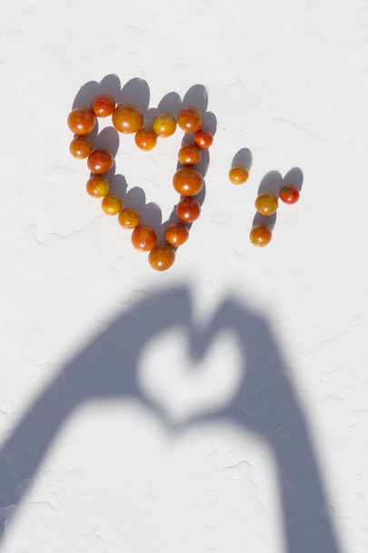 Kirschtomaten bilden ein Herz. Konzeptfoto, das darauf hinweist, wie gesund Gemüse ist. - Foto, Bild