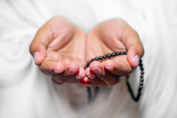 Muzułmanki podnoszą ręce, by modlić się z Tasbeeh na białym tle, wewnątrz. Skup się na rękach.. - Zdjęcie, obraz