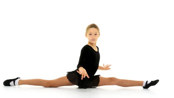 Slender girl gymnast doing the twine. The concept of childrens sport. - Photo, Image
