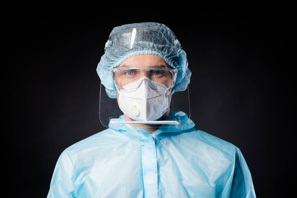 Closeup photo of guy expert doc virology center covid19 protection wear respiratory mask hazmat blue uniform suit plastic facial shield glasses isolated black color background - 写真・画像
