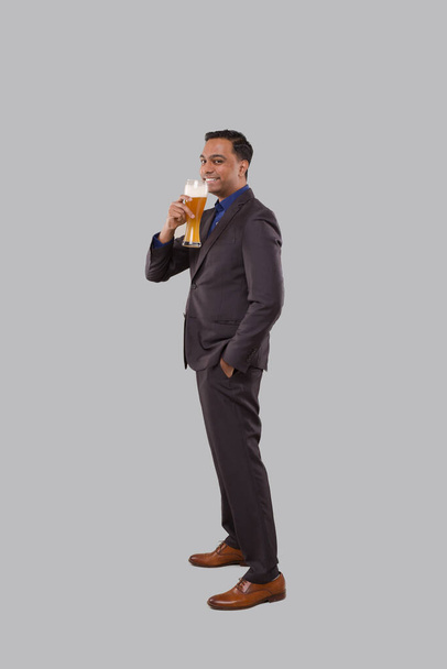 Üzletember sört iszik az Üvegből. Indiai üzletember Álló teljes hosszúságú sör a kézben - Fotó, kép