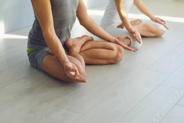 Close up of yoga couple people hand sitting relaxation in lotus field on floor in studio class. - Valokuva, kuva