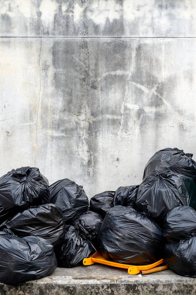 schwarzer Müllsack mit altem Backsteinmauerhintergrund - Foto, Bild
