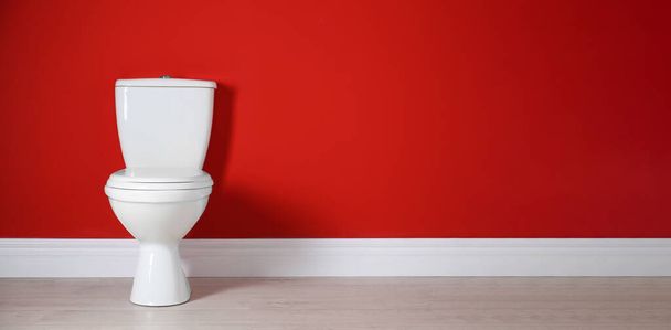 Toilet bowl near red wall in restroom, space for text. Banner design - Fotografie, Obrázek