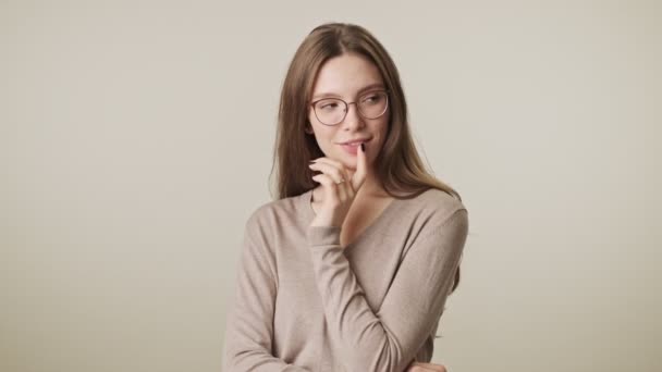 Beautiful young thinking thoughtful pretty woman wearing glasses isolated over grey wall background - Filmagem, Vídeo
