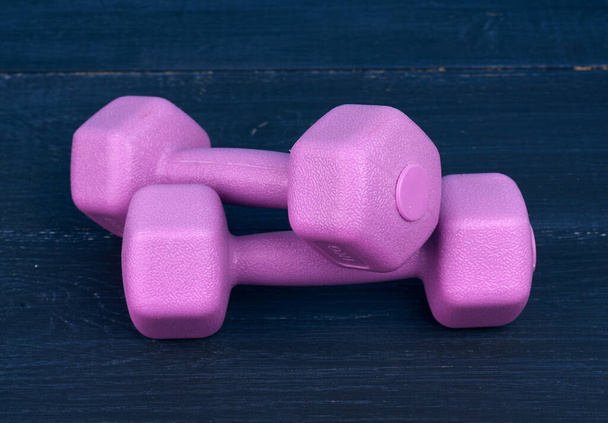 roze plastic halters van 1 kilogram op een blauwe achtergrond, sportuitrusting - Foto, afbeelding