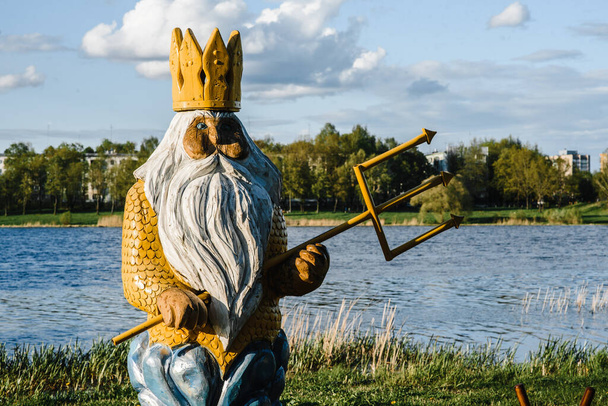 estátua de deus neptune feito de madeira com um tridente e uma grande barba cinza e uma coroa em sua cabeça contra
  - Foto, Imagem
