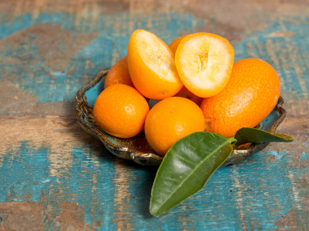 Смачні маленькі цитрусові фрукти апельсинові кумквати крупним планом на дерев'яному столі
 - Фото, зображення