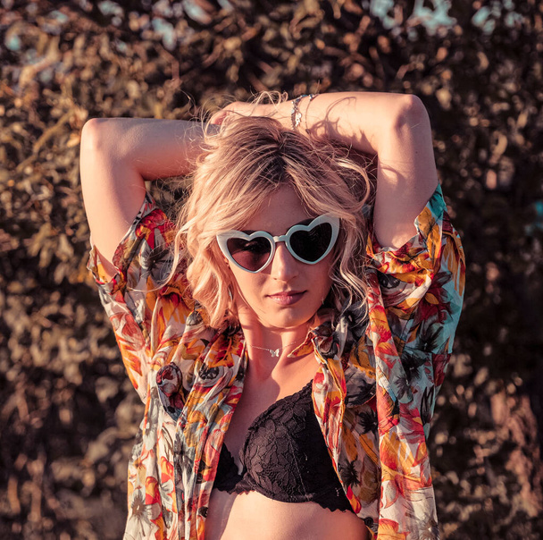 kaunis blondi tyttö poseeraa vehnäpellolla alusvaatteet ja aurinkolasit. Laadukas kuva - Valokuva, kuva