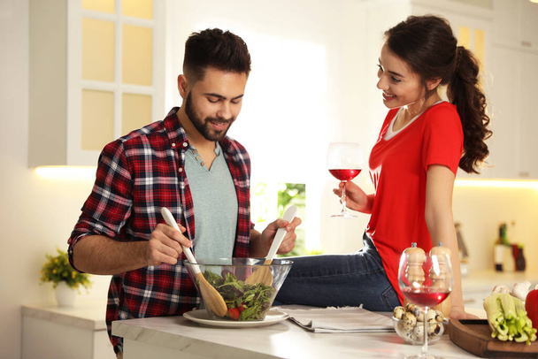 Lovely young couple cooking salad together in kitchen - Photo, Image