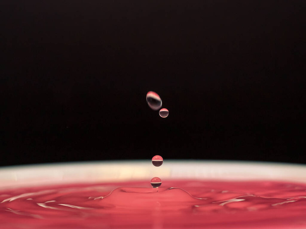 Gota de color rosa y salpicadura en el agua, congelación emoción caída
 - Foto, Imagen