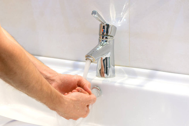 Nahaufnahme eines jungen kaukasischen Mannes, der sich im Waschbecken des Badezimmers die Hände mit Seife wäscht Körperhygiene, Schutz vor Viren und Bakterien. - Foto, Bild