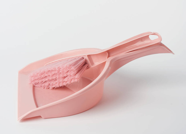pelle en plastique rose et brosse de nettoyage sur fond blanc - Photo, image