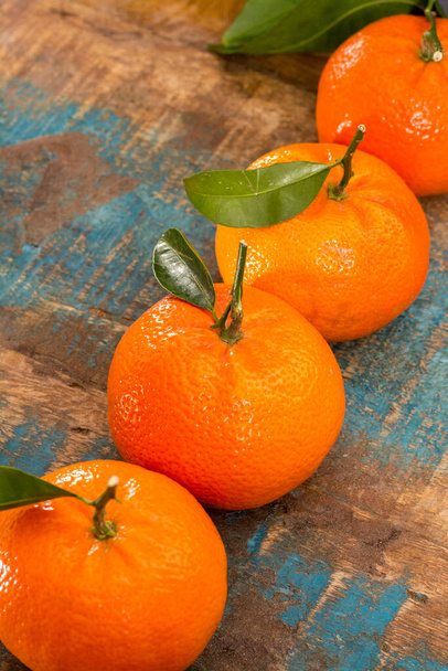 Rijp kleurrijke tropische citrusvruchten, mandarijnen of clementines van dichtbij op blauwe houten tafel - Foto, afbeelding