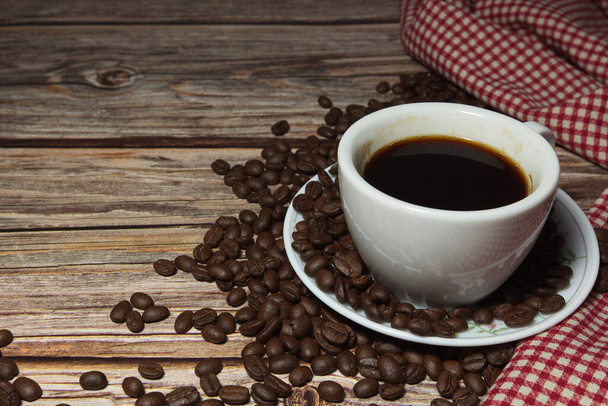 xícaras de café e grãos de café e pano xadrez vermelho em um fundo de madeira, de perto
 - Foto, Imagem