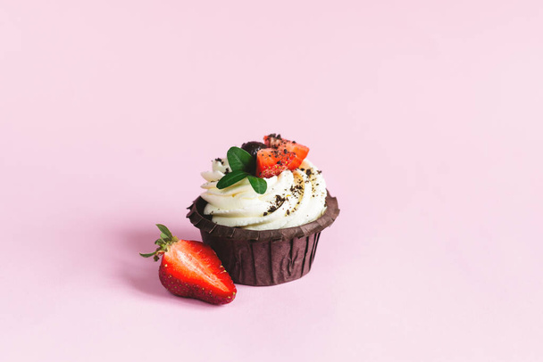 Maukas cupcake, koristeltu tuoretta mansikkaa vaaleanpunainen pastelli tausta. Tekstipaikka. - Valokuva, kuva
