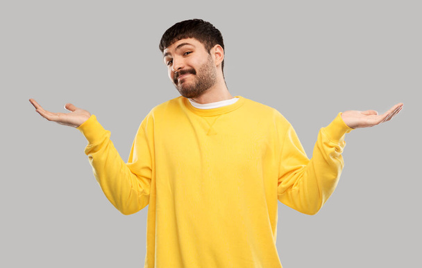 confused man in yellow sweatshirt shrugging - Φωτογραφία, εικόνα