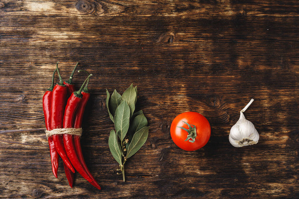 Top view of chili pepper, garlic and herbs on dark wooden surface - Valokuva, kuva