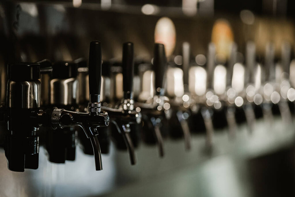 metallic beer taps in a empty bar - Fotó, kép
