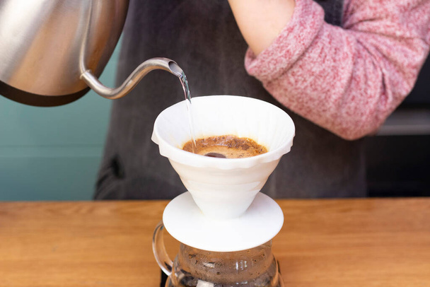 barista makes espresso using a funnel. The process of making coffee in the prover. Spilling coffee through the filter funnel from the kettle. - Fotoğraf, Görsel
