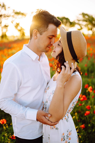 Loving couple in the poppy field. Loving couple hug one another during romantic date in poppy field. Enjoying time together. The concept of youth, love and lifestyle. - Foto, Imagen