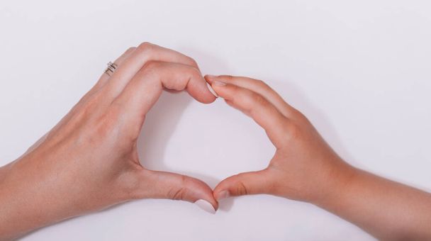 Rakkaus sydän kädessä. Äidin ja lapsen käsi tekee sydämen muodon yhdessä valkoisella taustalla. Maailman humanitaarisen päivän käsite. - Valokuva, kuva
